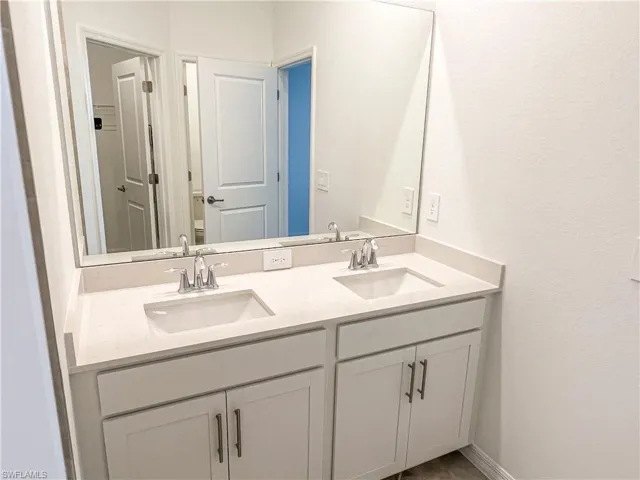 Bathroom featuring double vanity and a textured wall