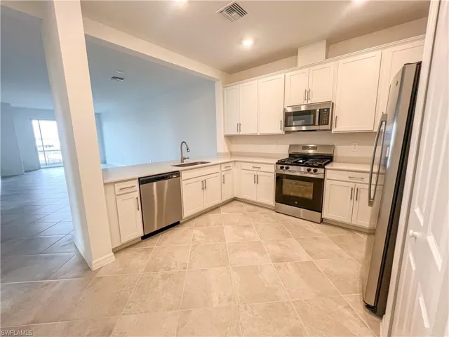 Kitchen featuring stainless steel appliances, white cabinetry, recessed lighting, a peninsula, and open floor plan