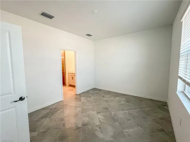 Unfurnished bedroom featuring baseboards and connected bathroom
