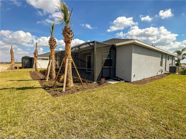 Rear view of property featuring a sunroom, a lanai, stucco siding, and a lawn