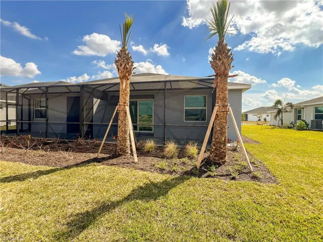 Back of property with glass enclosure, a sunroom, a yard, and stucco siding
