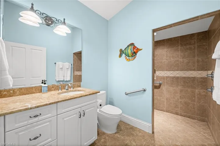 Spacious walk-in shower, extended vanity, and coastal accents throughout.