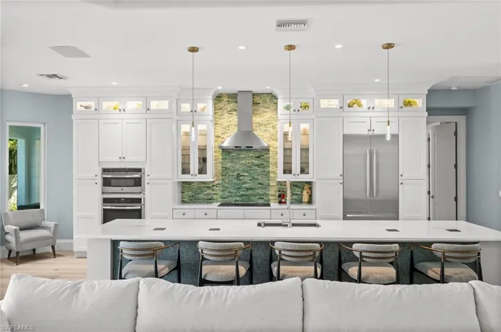 Thermador appliances, custom cabinetry, and a striking green tile accent wall create a showpiece kitchen for any home chef.