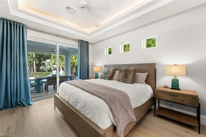 Spacious bedroom with warm wood flooring, lush views, and direct access to outdoor relaxation.