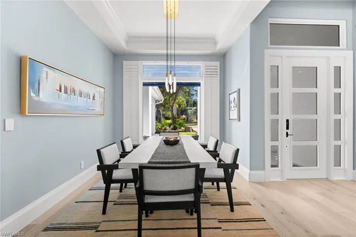 A refined dining space with high ceilings, glass-paneled entry, and natural sunlight throughout.