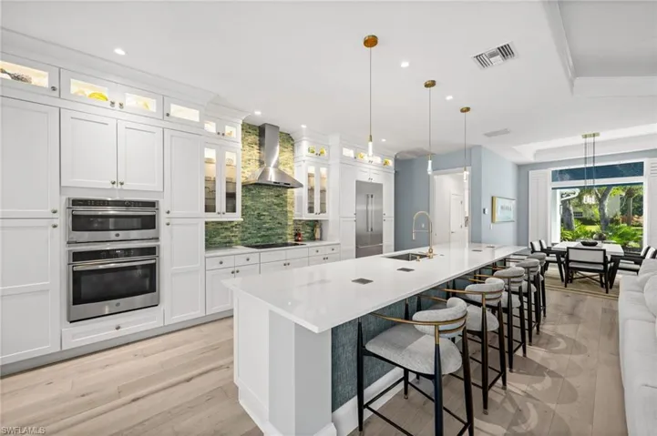 Plenty of seating at the oversized island, beautiful lighting, and open flow to dining + living for effortless hosting.