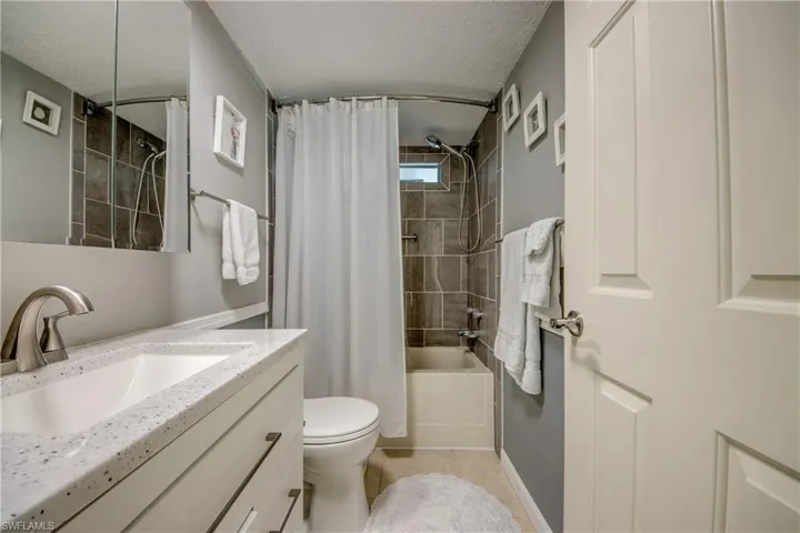 Full bathroom featuring a textured ceiling, shower / bath combo with shower curtain, vanity, and light tile patterned flooring