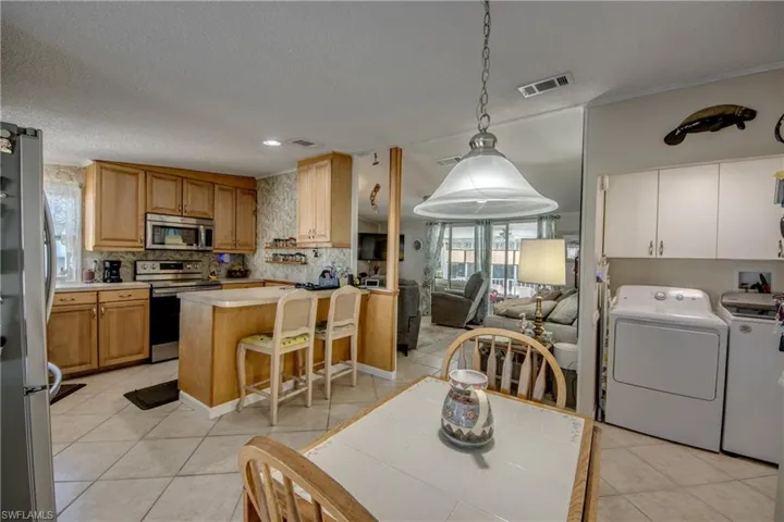 Kitchen with appliances with stainless steel finishes, light countertops, light tile patterned flooring, a peninsula, and a breakfast bar area