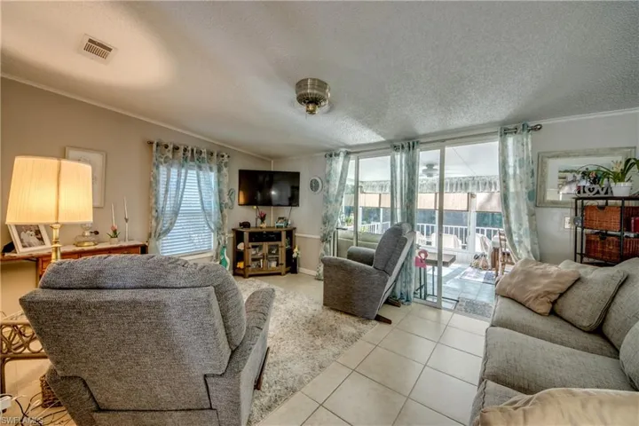 Living area featuring ornamental molding, a textured ceiling, and tile patterned flooring