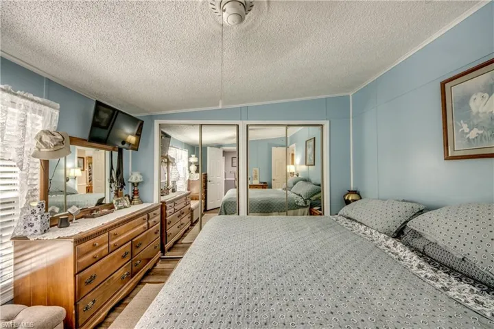 Bedroom featuring multiple closets, wood finished floors, crown molding, a decorative wall, and a textured ceiling