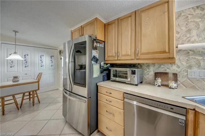 Kitchen featuring light countertops, stainless steel appliances, light tile patterned floors, hanging light fixtures, and backsplash