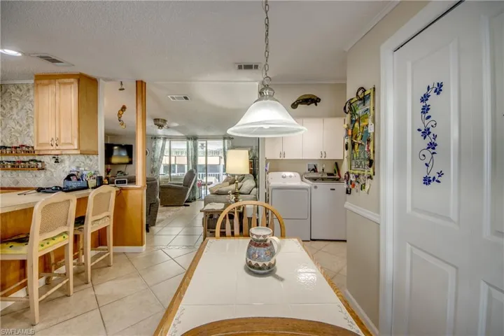 Dining space with light tile patterned floors, a textured ceiling, and washer and dryer