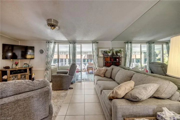 Living room with a textured ceiling, ornamental molding, tile patterned floors, and a wall of windows