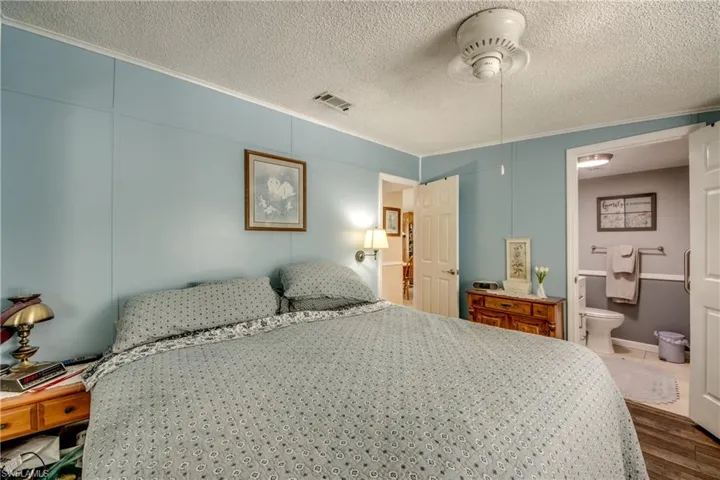 Bedroom with ornamental molding, wood finished floors, and a textured ceiling