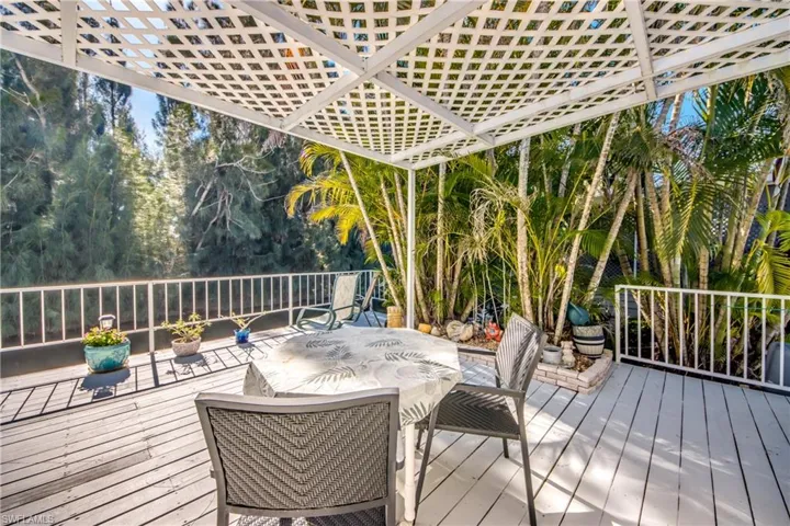 Deck with outdoor dining area and view of wooded area
