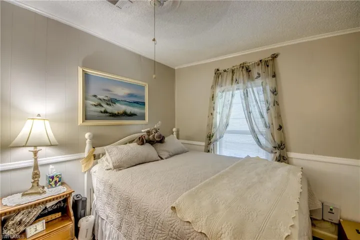 Bedroom with crown molding, wood walls, and a textured ceiling