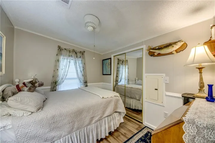 Bedroom featuring wood finished floors, a textured ceiling, a closet, and crown molding