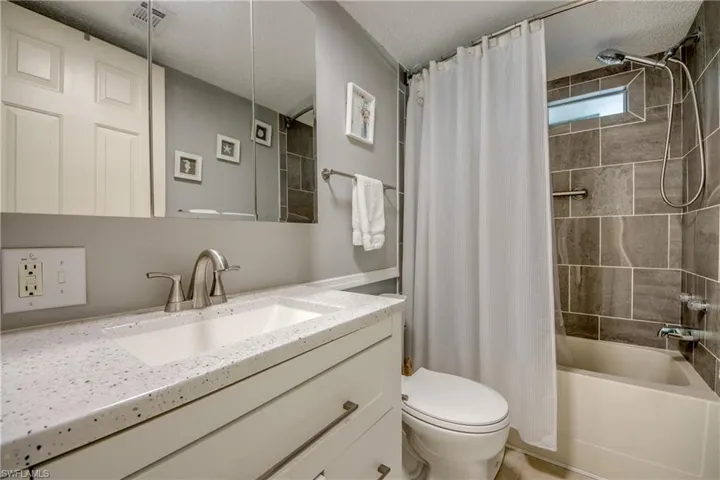 Bathroom featuring vanity, shower / bath combo with shower curtain, and a textured ceiling