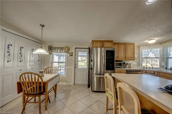Kitchen featuring light countertops, smart refrigerator, a breakfast bar, plenty of natural light, and a textured ceiling