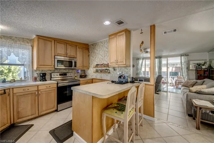 Kitchen with a kitchen breakfast bar, light tile patterned floors, appliances with stainless steel finishes, open floor plan, and a textured ceiling