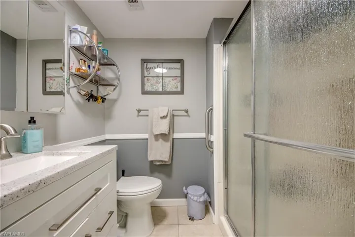 Bathroom with light tile patterned flooring, vanity, and a stall shower