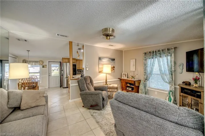 Living area featuring light tile patterned floors, a textured ceiling, and ornamental molding