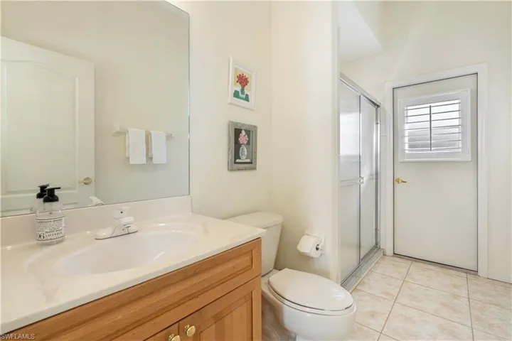 Bathroom with tile patterned floors, walk in shower, vanity, and toilet
