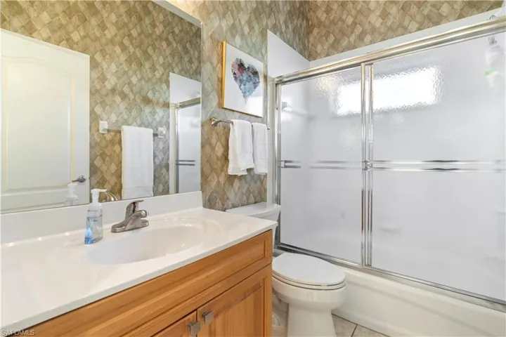 Full bathroom with tile patterned flooring, vanity, toilet, and shower / bath combination with glass door