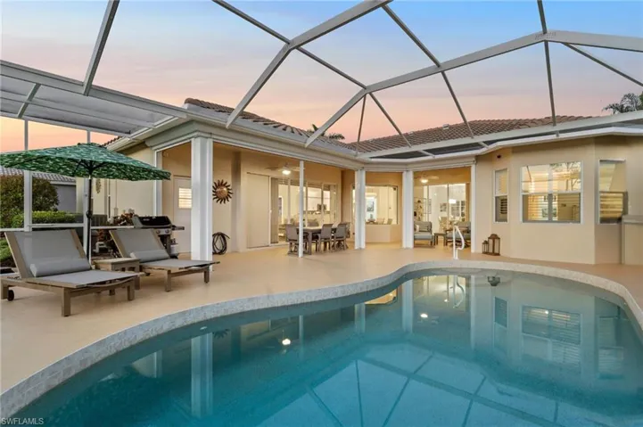 Back house at dusk featuring glass enclosure and a patio area