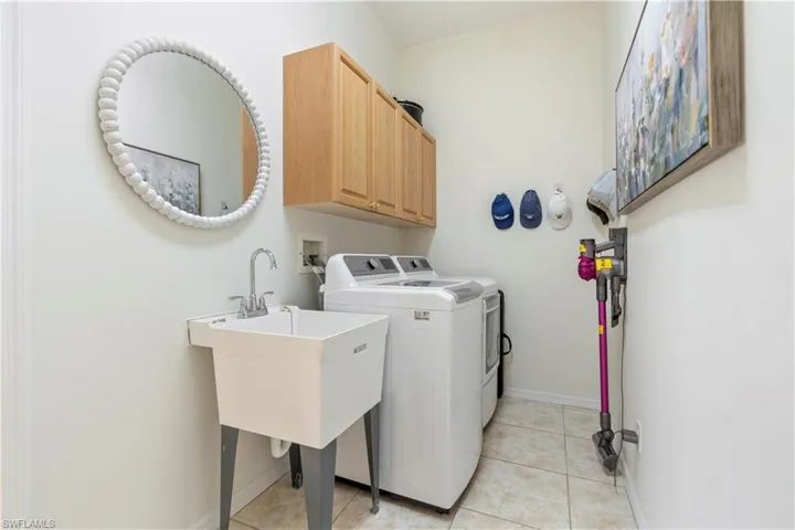 Washroom with washer and clothes dryer, cabinets, and light tile patterned floors