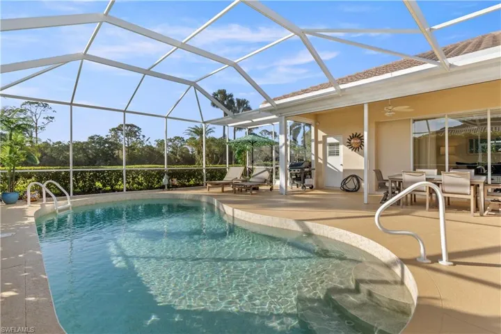 View of swimming pool with glass enclosure, ceiling fan, a patio, and grilling area