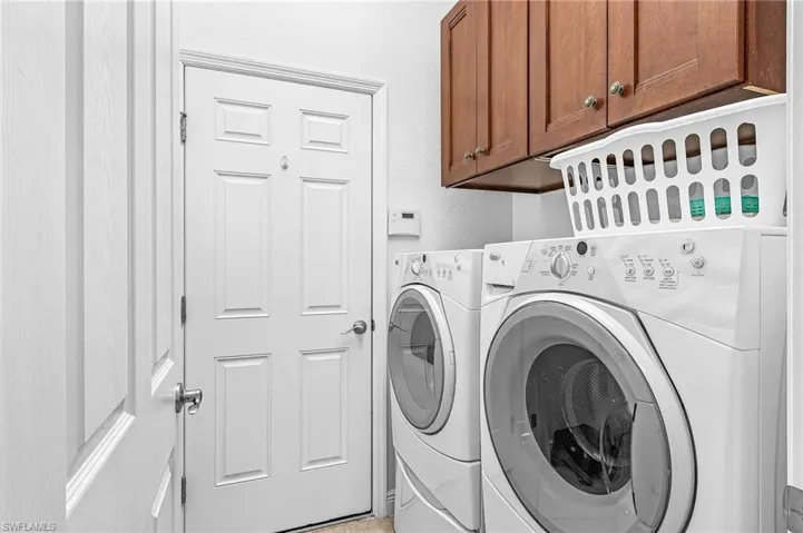 Laundry room with separate washer and dryer, cabinet space, and a textured wall