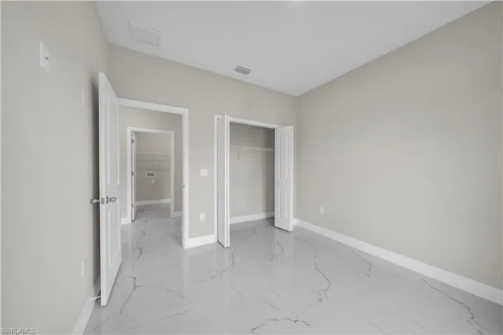 Unfurnished bedroom with a closet and light marble finish flooring