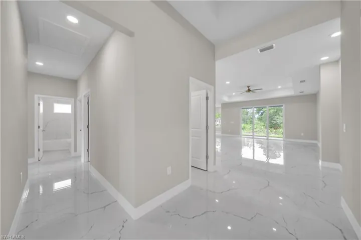 Corridor featuring recessed lighting, healthy amount of natural light, and light marble finish floors