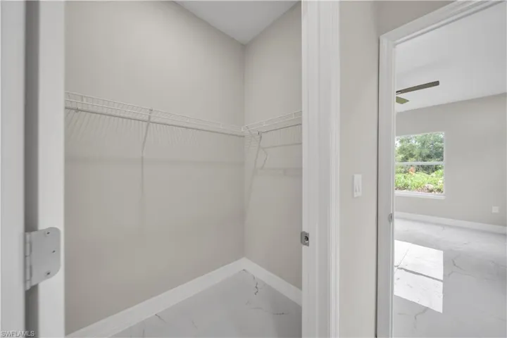 Walk in closet featuring marble finish floors and ceiling fan