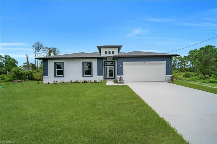 Prairie-style house featuring stucco siding, a front lawn, concrete driveway, and an attached garage