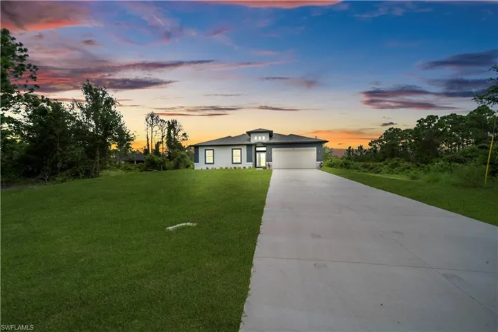 Prairie-style house featuring concrete driveway, a yard, and an attached garage