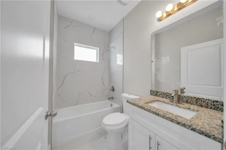 Bathroom with vanity, shower / bath combination, and marble finish floors