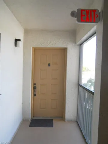 View of exterior entry with a balcony and stucco siding