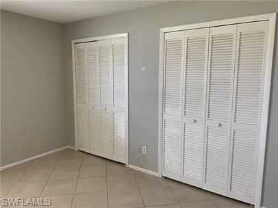 Unfurnished bedroom featuring multiple closets, light tile patterned floors, and a textured ceiling
