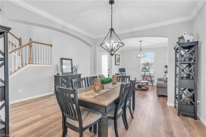 Dining space featuring hardwood / wood-style floors, crown molding, and a chandelier