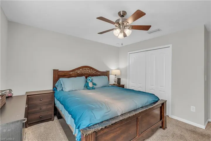 Bedroom featuring a closet, ceiling fan, and light colored carpet