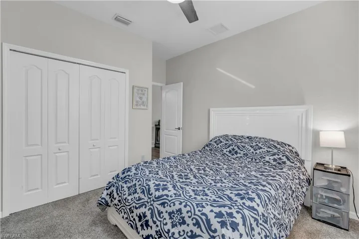 Carpeted bedroom featuring ceiling fan and a closet