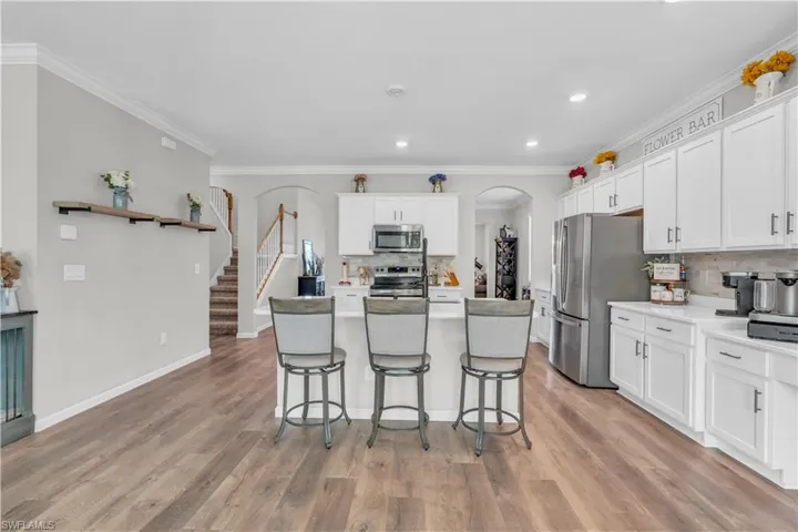 Kitchen with ornamental molding, stainless steel appliances, white cabinets, a center island, and light hardwood / wood-style floors