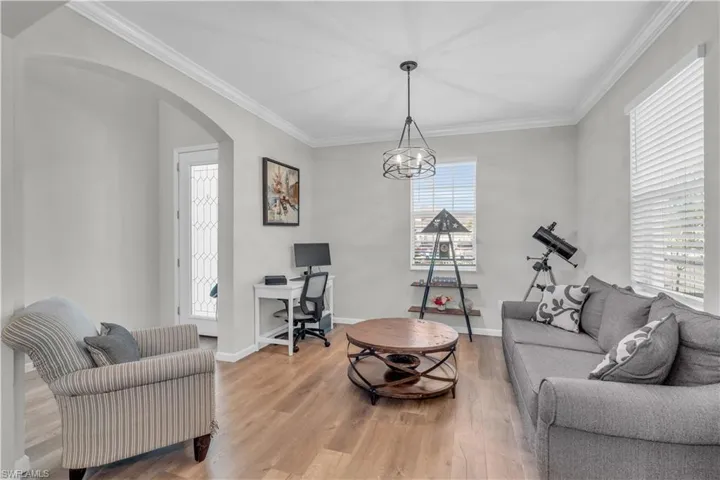 Living room with hardwood / wood-style floors, an inviting chandelier, and ornamental molding
