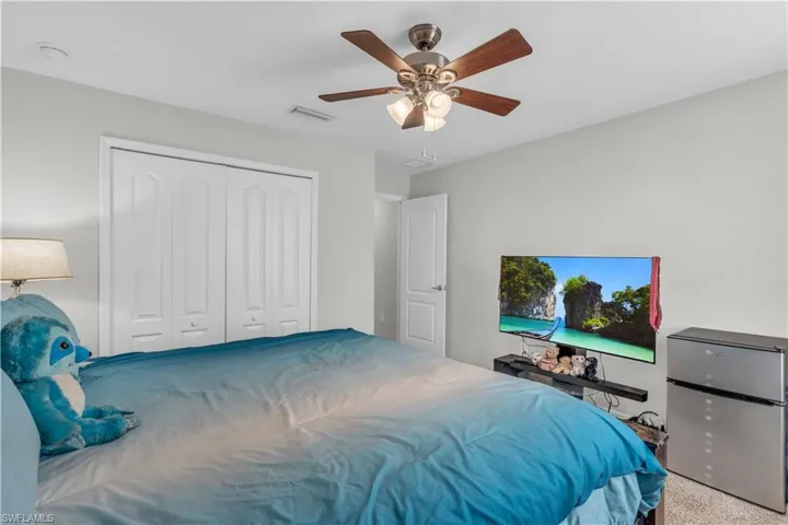Carpeted bedroom featuring ceiling fan and a closet