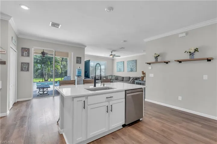 Kitchen featuring dishwasher, white cabinets, sink, light wood-type flooring, and an island with sink