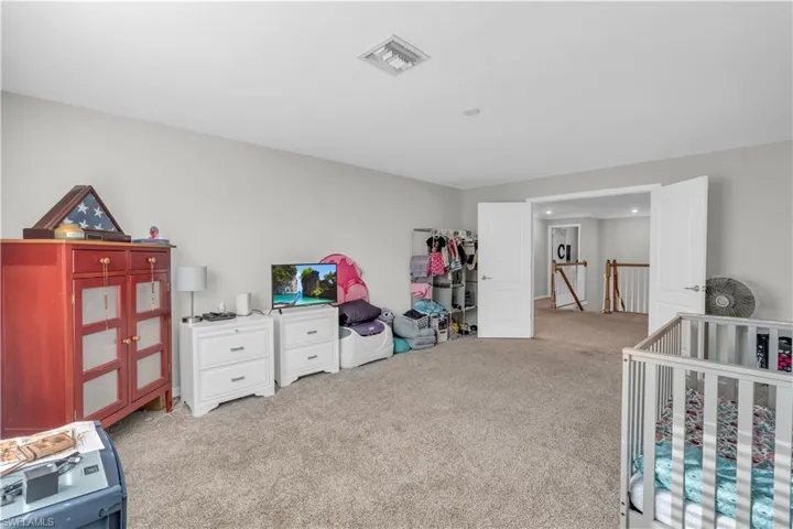 Carpeted bedroom featuring a nursery area