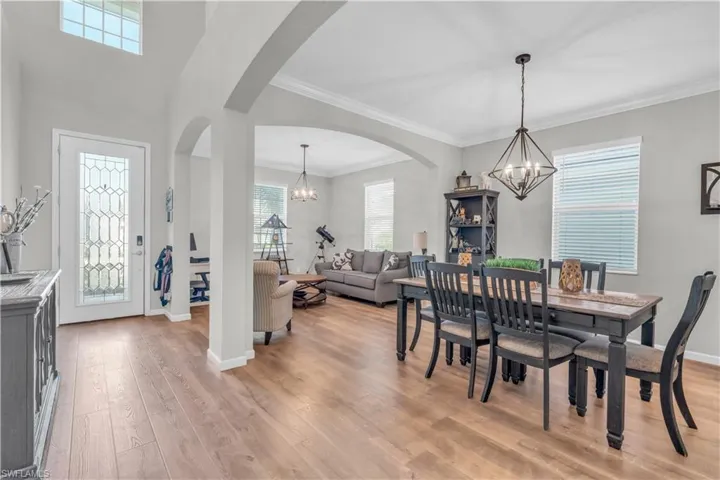 Dining space with ornamental molding, a notable chandelier, and light wood-type flooring
