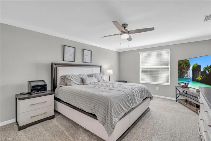 Bedroom with light colored carpet, ceiling fan, and ornamental molding